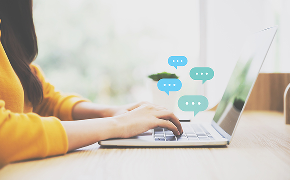 a woman typing on a laptop with speech bubbles above her hands